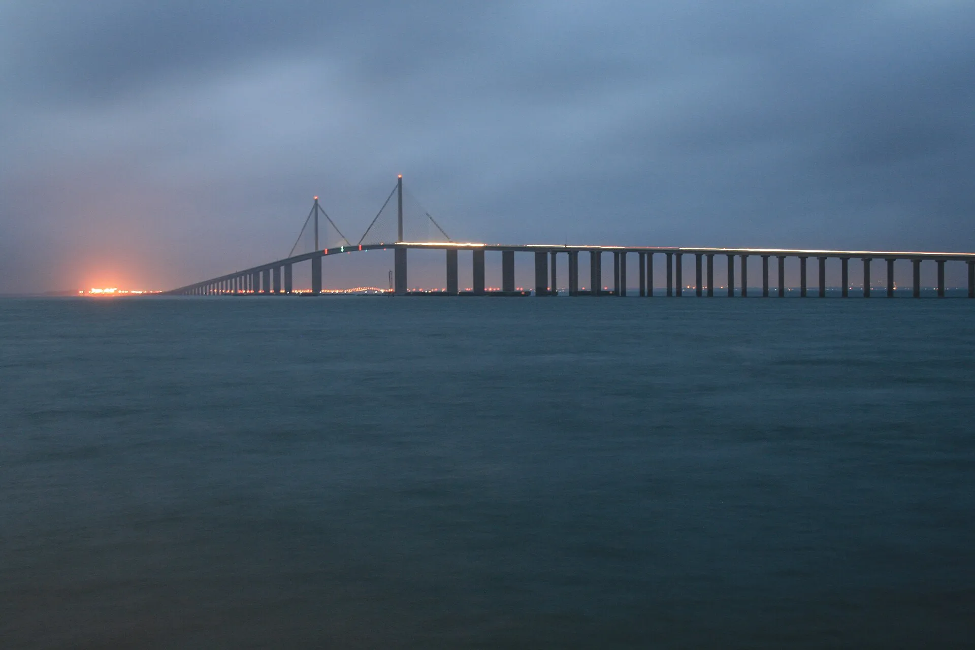 The Sunshine Skyway Bridge crossing Tampa Bay at dusk, its roadway lit along the full span